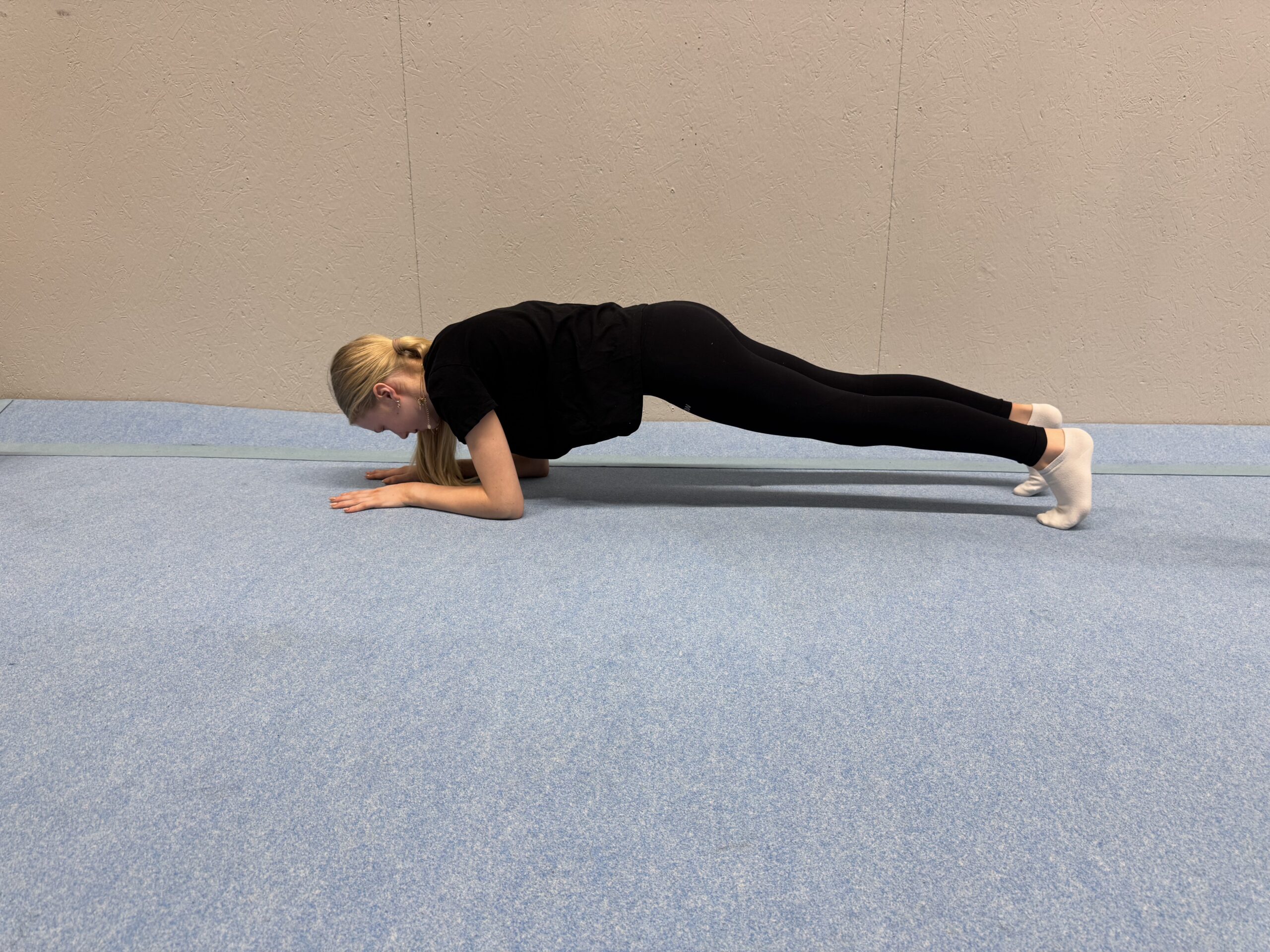 Novalie utför plankposition på golv.